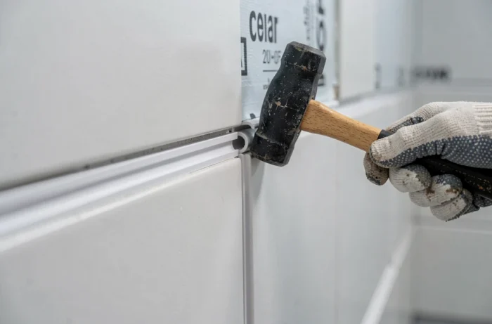 Détail de l'assemblage d'un panneau Vipanel avec maillet en caoutchouc dans une salle de bain